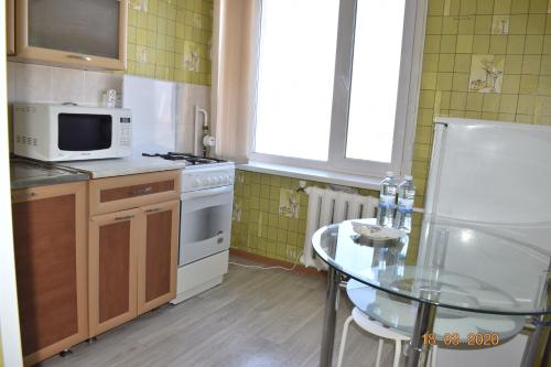 une petite cuisine avec une table en verre et un four micro-ondes dans l'établissement 1 комнатные апартаменты на Ауэзова 236, à Kökşetaw