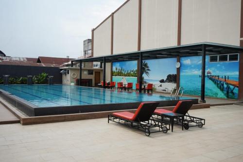 a large swimming pool with two chairs in front of a building at Comforta Dumai in Dumai