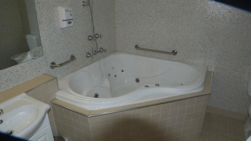 a bath tub in a bathroom with a sink at Golden Leaf Motel in Myrtleford