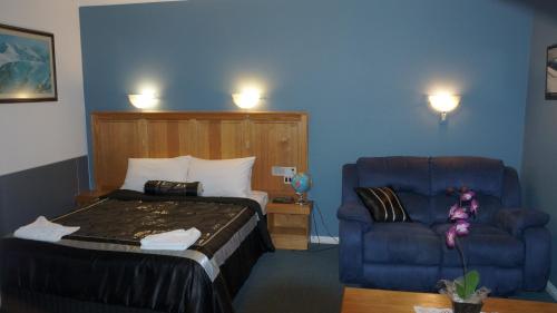 a bedroom with a bed and a couch and a chair at Golden Leaf Motel in Myrtleford