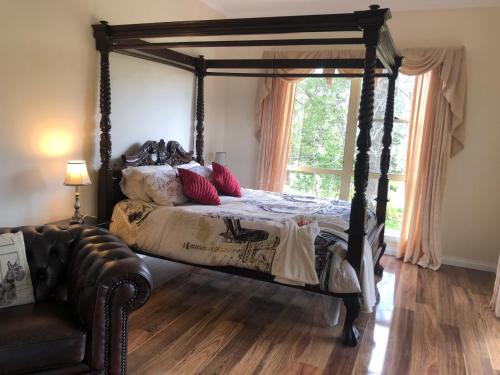 a bedroom with a canopy bed and a couch at Toolebewang Farm Cottage in Launching Place