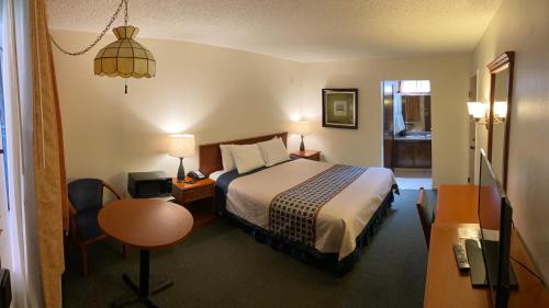 a hotel room with a bed and a desk and a table at Vantage Point Inn - Woodland Hills in Woodland Hills
