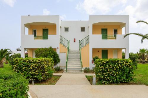 a white house with green doors and stairs at Sovereign Beach Hotel in Kardamaina