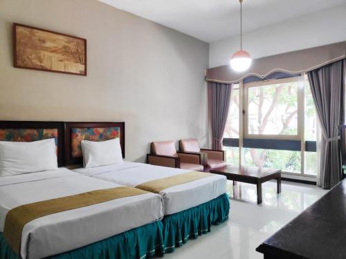a hotel room with two beds and a window at New Grand Park Hotel in Surabaya