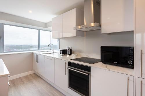 a kitchen with white cabinets and a sink and a microwave at Metro Apartments Dublin Airport in Dublin