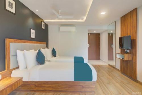 a bedroom with a large white bed and a television at Hotel Palm Beach Pride in Mumbai