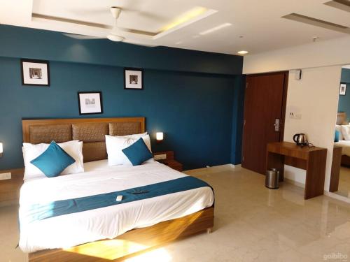 a bedroom with a large bed with a blue wall at Hotel Palm Beach Pride in Mumbai