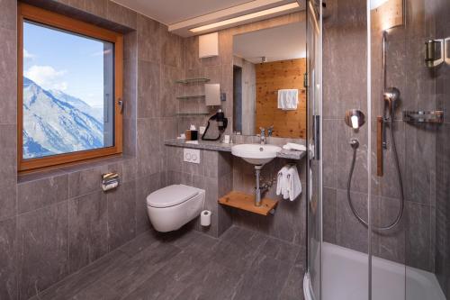 uma casa de banho com um WC, um lavatório e um chuveiro em Riffelhaus 1853 em Zermatt