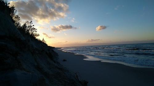 a sunset on a beach with the ocean at Agroturystyka Gawryś pokoje in Sasino