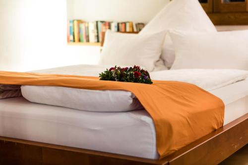 a bed with an orange blanket and flowers on it at Ferienwohnung in der Kirchgasse in Landshut