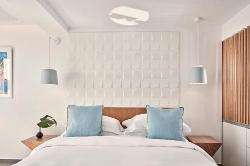 a bedroom with a bed with two blue pillows at Myconian Korali Relais & Chateaux in Mýkonos City