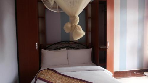 een slaapkamer met een bed met een gordijn en een raam bij Egret Pilgrims Inn in Kampala