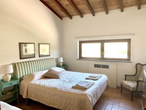 a bedroom with a bed and a window and a chair at Agriturismo Potrero Grande sul Lago di Martignano con spiaggia in Campagnano di Roma