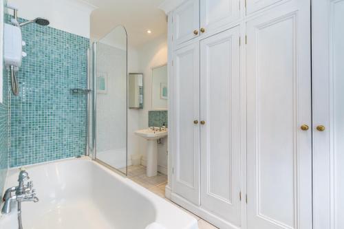 Baño blanco con bañera y lavamanos en Morleys Rooms - Located in the heart of Hurstpierpoint by Huluki Sussex Stays, en Hurstpierpoint