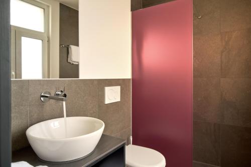 a bathroom with a white sink and a toilet at The HEY HOTEL in Interlaken