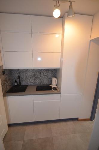 a kitchen with white cabinets and a sink at Blue Sail Sopot Apartments in Sopot
