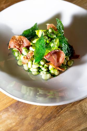 a white plate with a salad with peas and bacon at Mas de Torrent Hotel & Spa, Relais & Châteaux in Torrent