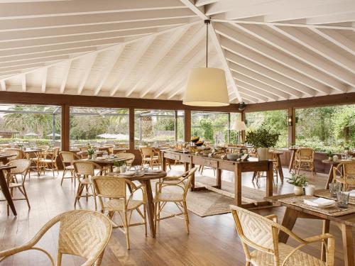 a restaurant with wooden tables and chairs and windows at Mas de Torrent Hotel & Spa, Relais & Châteaux in Torrent