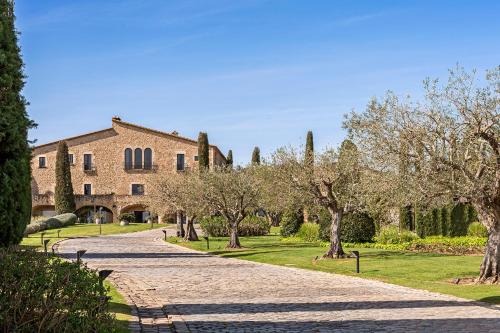 a cobblestone road in front of a building with trees at Mas de Torrent Hotel & Spa, Relais & Châteaux in Torrent