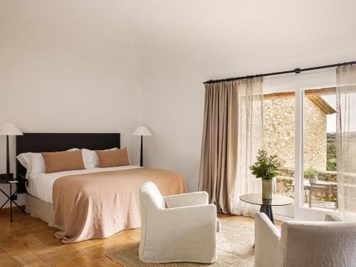 a bedroom with a bed and chairs and a window at Mas de Torrent Hotel & Spa, Relais & Châteaux in Torrent