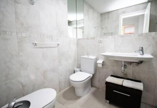 Baño blanco con aseo y lavamanos en Apartamentos Gema - Gemelos 26, en Benidorm