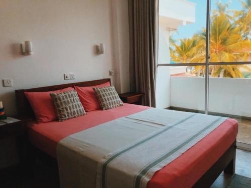 a bedroom with a large bed with a large window at Jasmine Garden Beach Guest House in Hikkaduwa