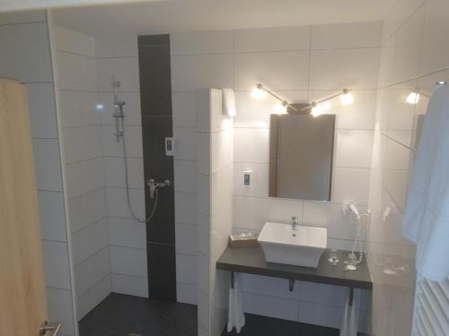 a bathroom with a sink and a shower with a mirror at Hotel Bohlje in Westerstede