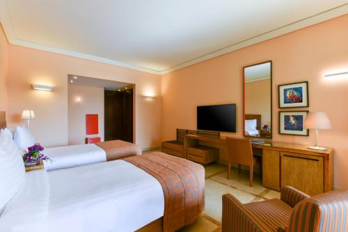 
a hotel room with two beds and a television at Kempinski Hotel Ishtar Dead Sea in Sowayma
