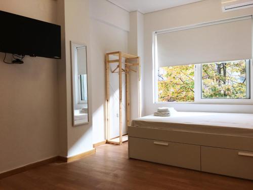 a bedroom with a bed with a window and a tv at Kinfeels' downtown apartment B2 in Larisa