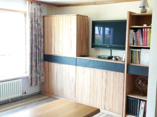 a living room with a tv and a book shelf at Ferienhaus Ainsen in Bad Füssing