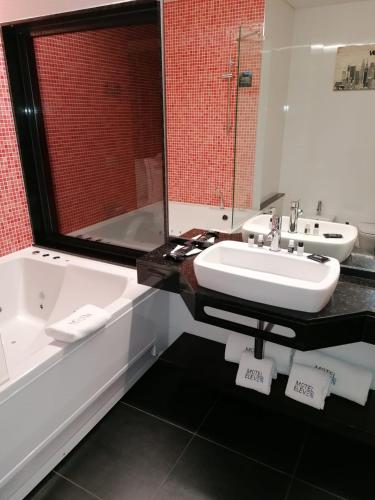 a bathroom with a tub and a sink and a bath tub at Motel Eleven in Leiria