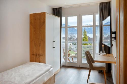 a bedroom with a bed and a desk and a window at Hotel Rössli Gourmet & Spa in Weggis