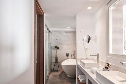 a white bathroom with a tub and a sink at Myconian Korali Relais & Chateaux in Mýkonos City