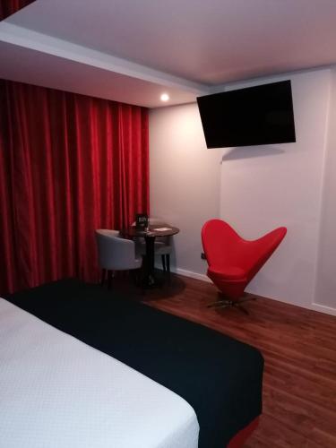a room with a bed and a red chair and a table at Motel Eleven in Leiria