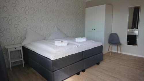 a bedroom with a bed with white sheets and a chair at Ostseehotel Kappeln by team SchleiFee in Kappeln