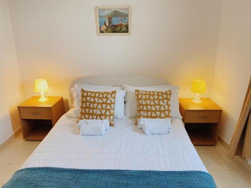 a bedroom with a white bed with two lamps at Apartments Sneki in Baošići