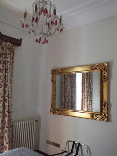 a mirror on a wall with a bed and a chandelier at Casa Palacio VillaZambra in Ronda