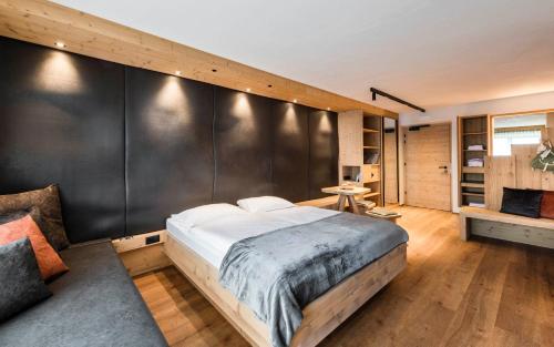 ein Schlafzimmer mit einem großen Bett und einer schwarzen Wand in der Unterkunft Family Home Alpenhof in Meransen