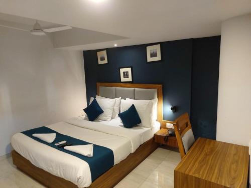 a bedroom with a large bed with a blue wall at Hotel Palm Beach Pride in Mumbai