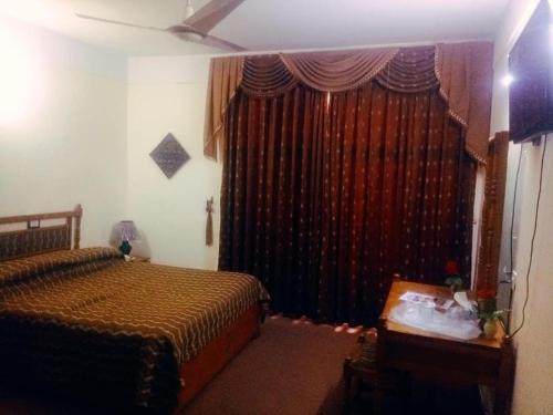 a bedroom with a bed and a window with curtains at Hotel Swat Regency in Swat