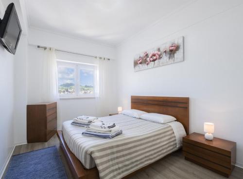 a white bedroom with a bed with towels on it at Volcanic Ocean View (Ponta Delgada historic center) in Ponta Delgada