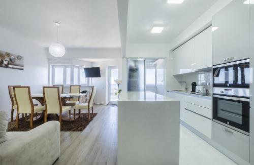 a white kitchen and dining room with a table and chairs at Volcanic Ocean View (Ponta Delgada historic center) in Ponta Delgada
