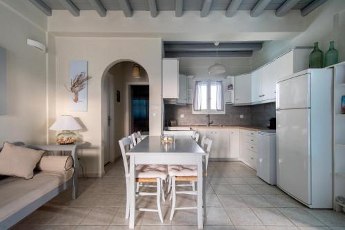 una cucina con tavolo e sedie bianchi e un divano di NAVA Devine Water Front House in Ambelas ad Ambelás