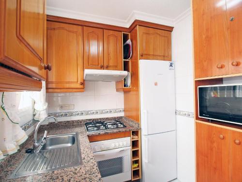 a small kitchen with wooden cabinets and a sink at Holiday Home Tamarit Beach by Interhome in Santa Pola