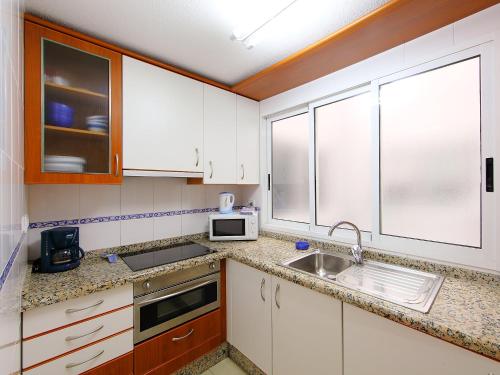 a kitchen with white cabinets and a sink and a microwave at Apartment Giner by Interhome in Benidorm