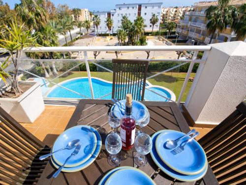 a table with blue plates and wine glasses on a balcony at Apartment Bahia Blanca-1 by Interhome in Denia