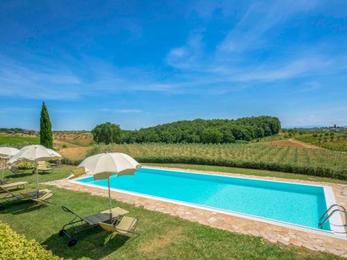 a swimming pool in a field with umbrellas at Holiday Home Vanessa by Interhome in Castelnuovo Berardenga