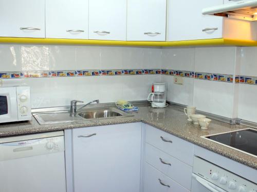 アルビールにあるApartment Estrella del Albir by Interhomeの白いキャビネット、シンク、電子レンジ付きのキッチンが備わります。