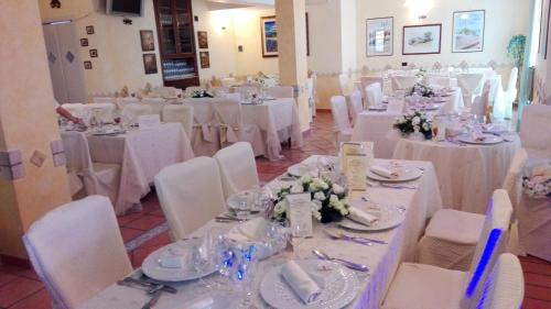 a room filled with tables and chairs with white linens at Hotel Di Nardo in Petacciato