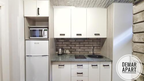 a kitchen with white cabinets and a refrigerator at DeMar Apart Violet in Lviv